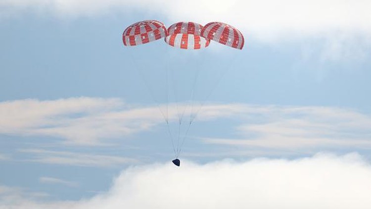 AT SEA, PACIFIC OCEAN - DECEMBER 11: NASAs Orion Capsule descends toward splash down after a successful uncrewed Artemis I Moon Mission on December 11, 2022 seen from aboard the U.S.S. Portland in the Pacific Ocean off the coast of Baja California, Mexico. A 26-day mission took the Orion spacecraft to the moon and back which completed a historic test flight that coincided with the 50th anniversary of the landing of Apollo 17 on the moon, the last time that NASA astronauts walked there. (Pool photo by Mario Tama/Getty Images)