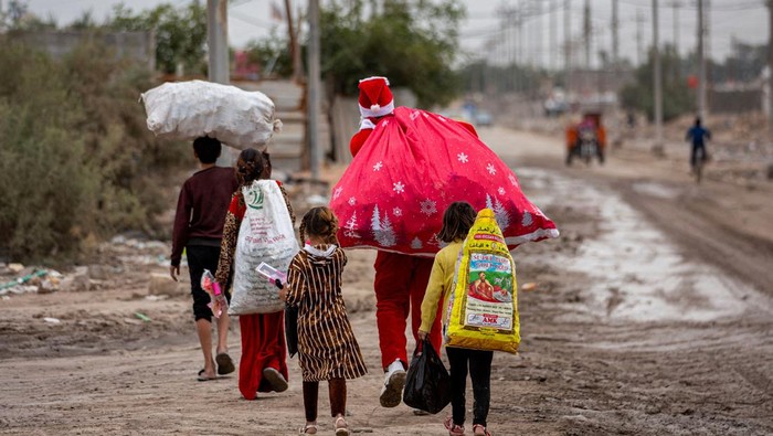 Anak-anak di Daerah Kumuh Irak Sambut Kedatangan βSinterklasβ Mohamed Maarouf, 28, while dressed in Saint Nicholas (Santa Claus) costume, distributes Christmas gifts to impoverished children living in slums near the centre of Iraq's southern city of Basra. (Photo by Hussein FALEH / AFP) (Photo by HUSSEIN FALEH/AFP via Getty Images)