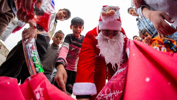 Mohamed Maarouf, 28, while dressed in Saint Nicholas (Santa Claus) costume, distributes Christmas gifts to impoverished children living in slums near the centre of Iraq's southern city of Basra. (Photo by Hussein FALEH / AFP) (Photo by HUSSEIN FALEH/AFP via Getty Images)