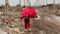 Seorang pria mengenakan kostum Sinterklas berjalan di daerah kumuh di pusat kota Basra, Irak.