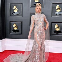 Naked dress juga dipopulerkan Paris Hilton yang mengenakan gaun dari koleksi Atelier Zuhra untuk tampil di Grammy Awards 2022. Sosialita kaya raya ini mengenakan gaun transparan dengan aksen metalik dan cape yang memberi kesan regal. Foto: Getty Images