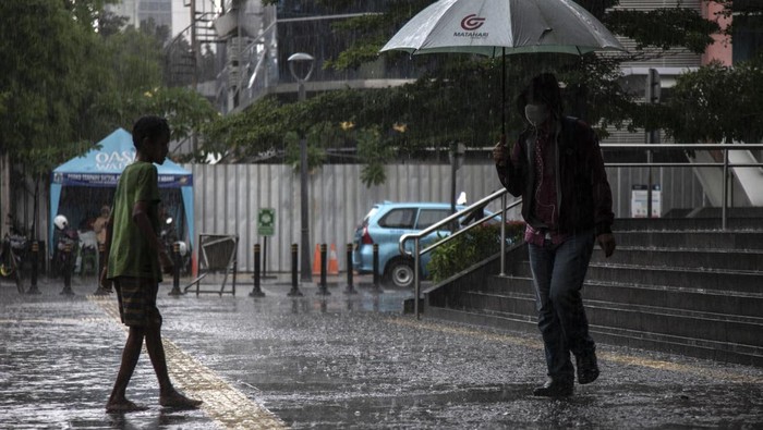 An umbrella services boy, standing waiting for pedestrians during a rainy day in Jakarta, on December 9, 2022.  (Photo by Aditya Irawan/NurPhoto via Getty Images)
