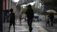 Anak-anak ini menawarkan penyewaan payung yang mereka bawa kepada para pejalan kaki.  
