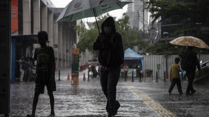 An umbrella services boy, standing waiting for pedestrians during a rainy day in Jakarta, on December 9, 2022.  (Photo by Aditya Irawan/NurPhoto via Getty Images)