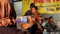 Seorang pengunjung mengabadikan momen penampilan musisi jalanan. Foto: Anggah/detikJateng