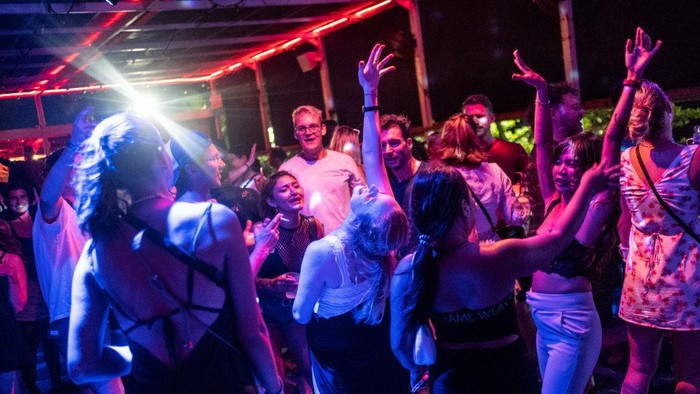 Potret Wisata Bali di Tengah Kisruh KUHP Baru CANGGU, BALI, INDONESIA - DECEMBER 7: Tourists gesture as they dance on a dance floor at a bar on December 7, 2022 in Canggu, Bali, Indonesia. Indonesia's parliament voted to pass a law that bans extramarital sex on Tuesday, in a move that critics quoted in local media have said will severely impact the tourism industry. Regions like Bali rely heavily on an influx of foreign tourists to keep their economies afloat, and the new law has raised concerns just as international arrivals start to pick up again post-pandemic. (Photo by Agung Parameswara/Getty Images)