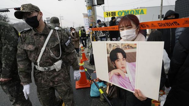 A fan waits for K-pop band BTS's member Jin to arrive before he enters the army to serve near an army training center in Yeoncheon, South Korea, Tuesday, Dec. 13, 2022. Jin, the oldest member of K-pop supergroup BTS, was set to enter a frontline South Korean boot camp Tuesday to start his 18 months of mandatory military service, as fans gathered near the base to say goodbye to their star. (AP Photo/Ahn Young-joon)