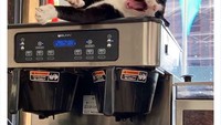 Kucing ini bisa disebut barista nggak ya? Terlihat ia nyaman tidur di atas mesin kopi.