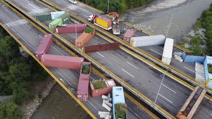 Venezuelan personnel remove containers that were blocking the Tienditas International Bridge, the international border between Venezuela and Colombia, in Cucuta, Colombia, Tuesday, Dec.12, 2022. Venezuelan President Nicolás Maduro announced his decision to fully open the border crossings with Colombia starting in January. (AP Photo/Maria Baron)