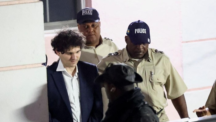 Sam Bankman-Fried, who founded and led FTX until a liquidity crunch forced the cryptocurrency exchange to declare bankruptcy, is escorted out of the Magistrate Court building after his arrest, in Nassau, Bahamas December 13, 2022. REUTERS/Dante Carrer