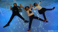Tiga orang anak dengan riang gembira bermain di instalasi dunia Avatar.  