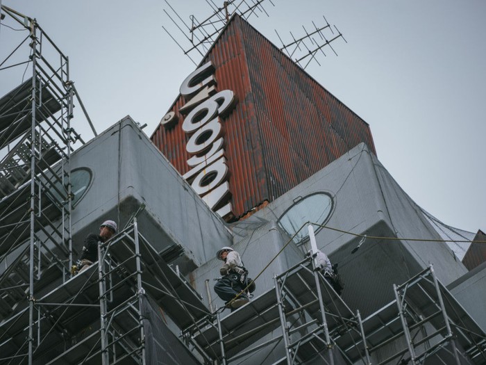 TOKYO, JAPAN - 2022/04/20: Construction workers install scaffolding as work begins to demolish the landmark Nakagin Capsule Tower, a mixed-use residential and office building constructed in the early 1970s and an example of Japan's postwar architectural design movement known as Metabolism, in Tokyo's Ginza district. (Photo by Nicolas Datiche/LightRocket via Getty Images)