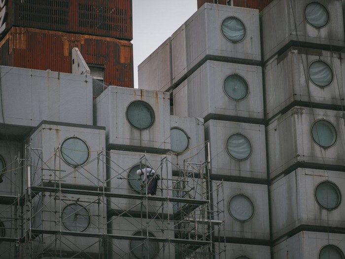 Nakagin Capsule TOKYO, JAPAN - 2022/04/20: Construction workers install scaffolding as work begins to demolish the landmark Nakagin Capsule Tower, a mixed-use residential and office building constructed in the early 1970s and an example of Japan's postwar architectural design movement known as Metabolism, in Tokyo's Ginza district. (Photo by Nicolas Datiche/LightRocket via Getty Images)