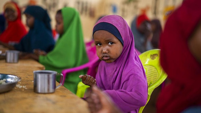 Potret Nelangsa Warga Somalia yang Lapar dan Kekeringan A child eats at a school in Dollow, Somalia, on Monday, Sept. 19, 2022. At midday, dozens of hungry children from the camps try to slip into a local primary school where the World Food Program offers a rare lunch program for students. (AP Photo/Jerome Delay)