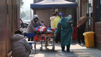 Para pekerja medis memindahkan seorang pasien yang demam di luar klinik di Wuhan. 10 Desember 2022. REUTERS/Martin Pollard.