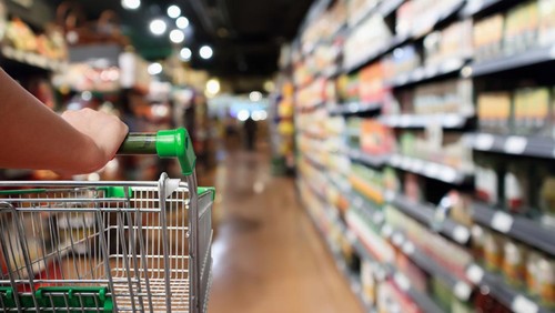 woman hand hold shopping cart with Abstract blur supermarket aisle background