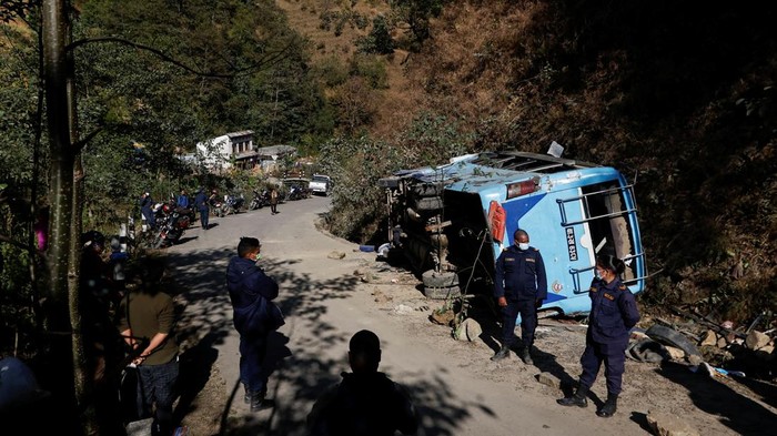 Penampakan Bus Maut yang Tewaskan Belasan Orang di Nepal Nepal police personnel stand guard near the wreckage of a bus where at least 18 people were killed, and 21 others were injured at Kavrepalanchok District outskirts of Kathmandu, Nepal December 14, 2022. REUTERS/Navesh Chitrakar