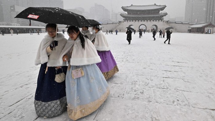Visitors wearing traditional hanbok dress walk through Gyeongbokgung palace during snowfall in central Seoul on December 15, 2022. (Photo by Jung Yeon-je / AFP) (Photo by JUNG YEON-JE/AFP via Getty Images)
