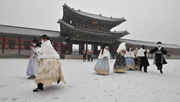 Visitors wearing traditional hanbok dress walk through Gyeongbokgung palace during snowfall in central Seoul on December 15, 2022. (Photo by Jung Yeon-je / AFP) (Photo by JUNG YEON-JE/AFP via Getty Images)