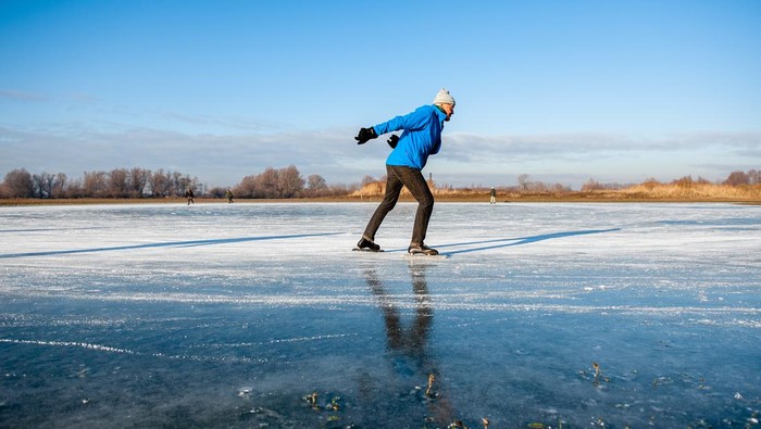 Asiknya Warga Belanda Berseluncur di Danau yang Membeku NIJMEGEN, NETHERLANDS - 2022/12/15: An old man is seen skating on natural ice. After three days of sub-zero temperatures (around -7 degrees Celsius during the night), the water of some lakes froze. Some skaters took the chance despite the low levels of water, that provided a small part of ice surface large enough to skate, on the 'Oude Waal' lake. (Photo by Ana Fernandez/SOPA Images/LightRocket via Getty Images)