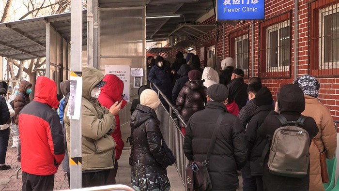 This frame grab from AFPTV video footage shows an elderly woman being assisting by a health worker and a man as she waits outside a fever clinic amid the Covid-19 pandemic in Beijing on December 14, 2022. (Photo by Yuxuan ZHANG / various sources / AFP) (Photo by YUXUAN ZHANG/AFPTV/AFP via Getty Images)
