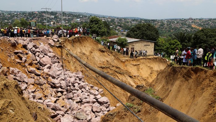 People look at a damaged road after heavy rains caused floods and landslides, on the outskirts of Kinshasa, Democratic Republic of Congo December 14,2022. REUTERS/Justin Makangara