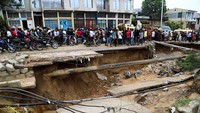 Warga melewati jalan yang rusak parah setelah hujan lebat menyebabkan banjir dan tanah longsor, di pinggiran Kinshasa.  