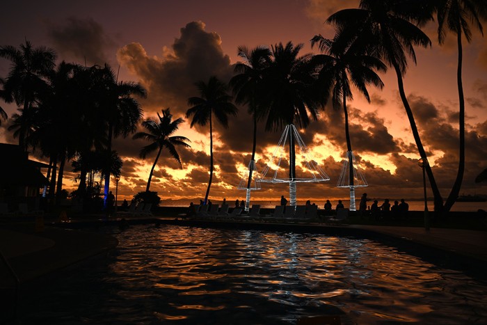 People are silhouetted against the setting sun as they spend their evening at the sea side in Suva on December 16, 2022. (Photo by SAEED KHAN / AFP) (Photo by SAEED KHAN/AFP via Getty Images)