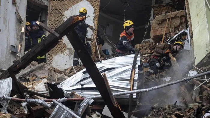 Ukrainian State Emergency Service firefighters work at the building which was destroyed by a Russian attack in Kryvyi Rih, Ukraine, Friday, Dec. 16, 2022. Russian forces launched at least 60 missiles across Ukraine on Friday, officials said, reporting explosions in at least four cities, including Kyiv. At least two people were killed by a strike on a residential building in central Ukraine, where a hunt was on for survivors. (AP Photo/Evgeniy Maloletka)