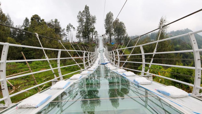 Potret Uji Coba Jembatan Kaca 120 Meter Pakai Karung Pasir Total 7 Ton Kementerian Pekerjaan Umum dan Perumahan Rakyat (PUPR) telah menyelesaikan pembangunan Jembatan Kaca Seruni Point di Kawasan Strategis Pariwisata Nasional (KSPN) Bromo-Tengger-Semeru, Jawa Timur. Saat ini tengah dilakukan uji beban (loading test) pada Jembatan Kaca Seruni Point (prototype) untuk menguji performa struktur dan keamanan jembatan, sehingga memberikan jaminan keamanan dan keselamatan bagi wisatawan setelah dioperasikan nanti.