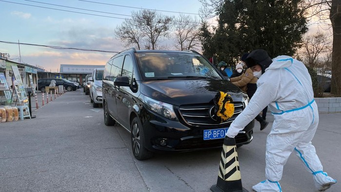 HEALTH-CORONAVIRUS/CHINA A worker in a protective suit removes a cone in front of a hearse outside funeral home, amid the coronavirus disease (COVID-19) outbreak in Beijing, China December 17, 2022. REUTERS/Alessandro Diviggiano