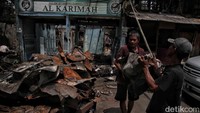 Tetangga korban kebakaran turut membantu membersihkan puing-puing sisa kebakaran.