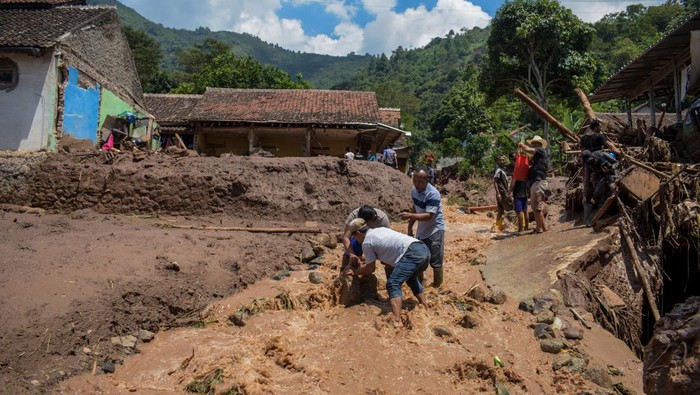 Warga membersihkan puing akibat banjir bandang di Sawahdadap, Cimanggung, Kabupaten Sumedang, Jawa Barat, Minggu (18/12/2022). Terjangan banjir bandang akibat intensitas hujan yang tinggi pada Sabtu (17/12/2022) petang tersebut mengakibatkan sejumlah rumah rusak dan ratusan warga mengungsi serta dua orang meninggal dunia. ANTARA FOTO/Ahmad Fauzan/rai/wsj.