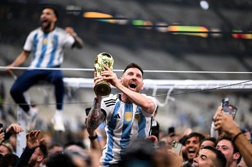 Argentina's forward #10 Lionel Messi lifts the FIFA World Cup Trophy as he celebrates with supporters winning the Qatar 2022 World Cup final football match between Argentina and France at Lusail Stadium in Lusail, north of Doha on December 18, 2022. (Photo by Kirill KUDRYAVTSEV / AFP)