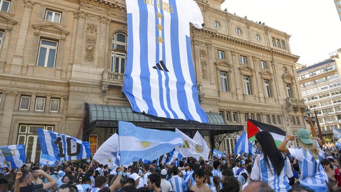 Ironi, Argentina Pestapora Juara Piala Dunia di Tengah Krisis Ekonomi A giant jersey of the Argentine national soccer team hangs on the front of the Colon Theater as fans celebrate their team's World Cup victory over France in Buenos Aires, Argentina, Sunday, Dec. 18, 2022. (AP Photo/Gustavo Garello)
