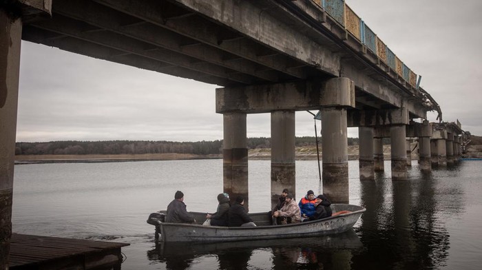 Jembatan Putus Dibom Rusia, Warga Kharkiv Nyeberang Naik Perahu KHARKIV, UKRAINE - DECEMBER 18: After Russian forces retreated from the area and destroyed the reservoir bridge, residents carry goods across the water by a free small taxi boat on December 18, 2022 in Staryi Saltiv, Kharkiv, Ukraine. Kharkiv, Ukraine's second city, was left without power for hours on Friday after the latest attack by Russia on the region's energy infrastructure. The city's mayor said it suffered