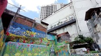 Mural mendominasi sepanjang jalan di Kampung Braga RW 08. Setelah melintasi mural yang luntur itu, ada pertigaan. Di lokasi ini, pengunjung kampung bisa melihat deretan tanaman di sepanjang jalan. (Foto: Sudirman Wamad/detikJabar)