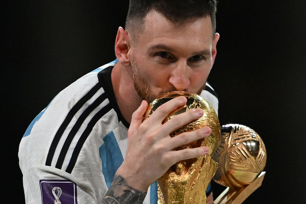 Kapten dan penyerang Argentina #10 Lionel Messi mencium Trofi Piala Dunia FIFA selama upacara trofi setelah Argentina memenangkan pertandingan sepak bola final Piala Dunia Qatar 2022 antara Argentina dan Prancis di Stadion Lusail di Lusail, utara Doha, Qatar, Minggu (18/12/2022). Argentina menjadi juara Piala Dunia 2022 setelah menang adu penalti atas Prancis 4-2. (Photo by PAUL ELLIS/AFP via Getty Images)