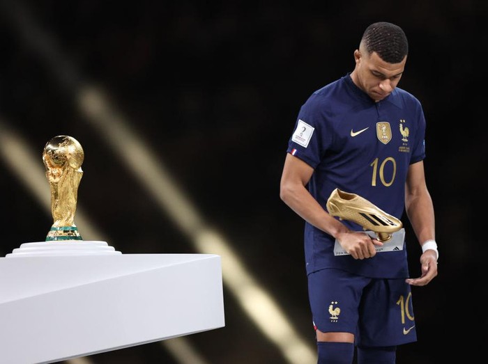 LUSAIL CITY, QATAR - DECEMBER 18: Kylian Mbappe of France walks past the FIFA World Cup Trophy after losing in the final with his golden boot trophy during the FIFA World Cup Qatar 2022 Final match between Argentina and France at Lusail Stadium on December 18, 2022 in Lusail City, Qatar. (Photo by Matthew Ashton - AMA/Getty Images)