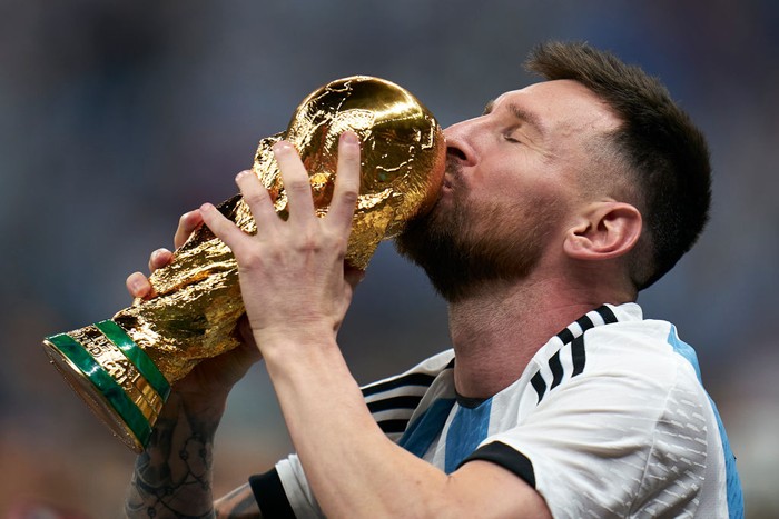 LUSAIL CITY, QATAR - DECEMBER 18: Lionel Messi of Argentina kisses the FIFA World Cup Qatar 2022 Winners Trophy after the FIFA World Cup Qatar 2022 Final match between Argentina and France at Lusail Stadium on December 18, 2022 in Lusail City, Qatar. (Photo by Quality Sport Images/Getty Images)