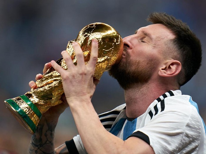 LUSAIL CITY, QATAR - DECEMBER 18: Lionel Messi of Argentina kisses the FIFA World Cup Qatar 2022 Winners Trophy after the FIFA World Cup Qatar 2022 Final match between Argentina and France at Lusail Stadium on December 18, 2022 in Lusail City, Qatar. (Photo by Quality Sport Images/Getty Images)