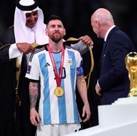 Setelah sukses menyabet gelar juara Piala Dunia 2022, Lionel Messi dan tim Albicelestes melakukan penyerahan trofi yang jadi perhatian. Dalam momen tersebut, Messi dipakaikan jubah hitam khas Arab yang menuai perdebatan. Foto: Getty Images/Amin Mohammad Jamali