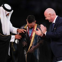 Sebelum mengangkat trofi kemenangan Golden Ball Messi diberi selamat oleh Presiden FIFA Gianni Infantino kemudian dipakaikan jubah oleh Emir Qatar Sheikh Tamim bin Hamad Al Thani sebagai kepala negara.Foto: Getty Images/Ian MacNicol