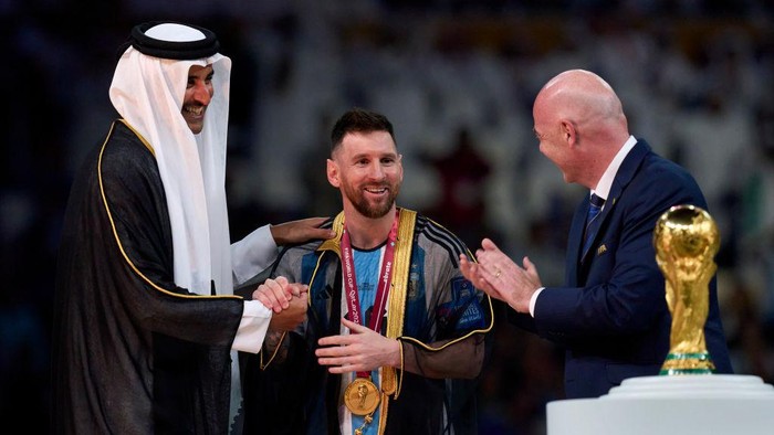 LUSAIL CITY, QATAR - DECEMBER 18: Lionel Messi of Argentina is presented with their FIFA World Cup Qatar 2022 trophy after the team's victory by Gianni Infantino, President of FIFA and Tamim bin Hamad Al Thani, Emir of Qatar, following the FIFA World Cup Qatar 2022 Final match between Argentina and France at Lusail Stadium on December 18, 2022 in Lusail City, Qatar. (Photo by Juan Luis Diaz/Quality Sport Images/Getty Images)