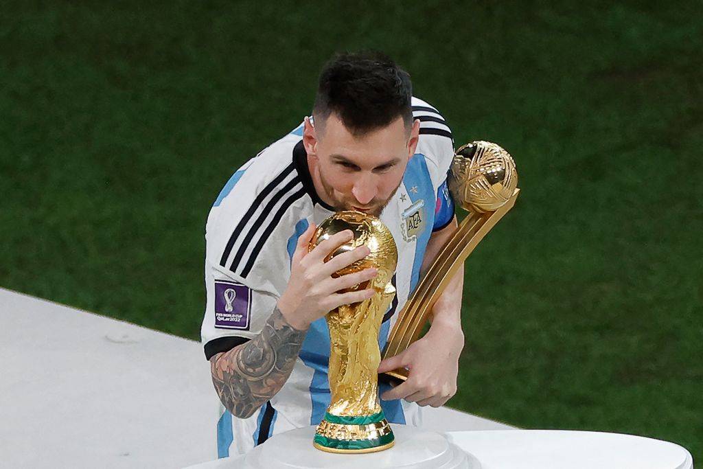 Pemain depan Argentina #10 Lionel Messi mencium trofi Piala Dunia setelah menerima penghargaan Bola Emas pada upacara trofi Piala Dunia Qatar 2022 setelah pertandingan final sepak bola Piala Dunia Qatar 2022 antara Argentina dan Prancis di Stadion Lusail di Lusail, utara Doha, Qatar, Minggu (18/12/2022).  Argentina menjadi juara Piala Dunia 2022 setelah menang adu penalti atas Prancis 4-2. (Photo by ODD ANDERSEN/AFP via Getty Images)