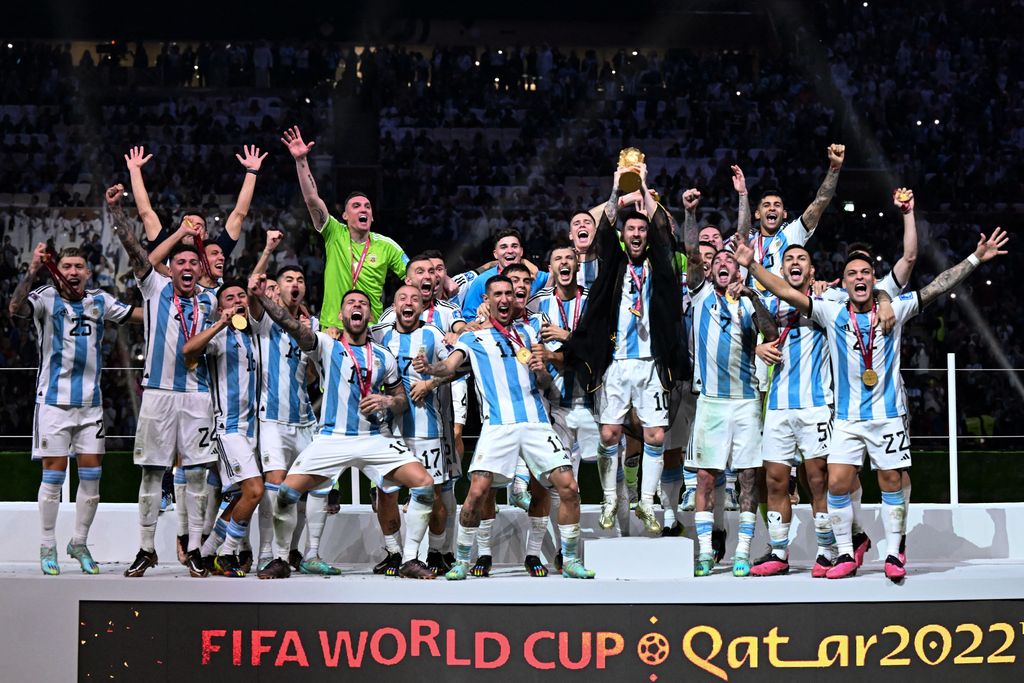 Penyerang Argentina #10 Lionel Messi mengangkat Trofi Piala Dunia FIFA saat ia merayakan dengan rekan setimnya usai memenangkan pertandingan sepak bola final Piala Dunia Qatar 2022 antara Argentina dan Prancis di Stadion Lusail di Lusail, utara Doha, Qatar, Minggu (18/12/2022). Argentina menjadi juara Piala Dunia 2022 setelah menang adu penalti atas Prancis 4-2. (Photo by KIRILL KUDRYAVTSEV/AFP via Getty Images)