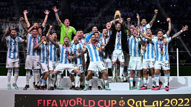 Penyerang Argentina #10 Lionel Messi mengangkat Trofi Piala Dunia FIFA saat ia merayakan dengan rekan setimnya usai memenangkan pertandingan sepak bola final Piala Dunia Qatar 2022 antara Argentina dan Prancis Penyerang Argentina #10 Lionel Messi mengangkat Trofi Piala Dunia FIFA saat ia merayakan dengan rekan setimnya usai memenangkan pertandingan sepak bola final Piala Dunia Qatar 2022 antara Argentina dan Prancis di Stadion Lusail di Lusail, utara Doha, Qatar, Minggu (18/12/2022). Argentina menjadi juara Piala Dunia 2022 setelah menang adu penalti atas Prancis 4-2. (Photo by KIRILL KUDRYAVTSEV/AFP via Getty Images)