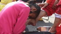 Setelah membasuk kaki sang ibu, seorang anak mencium kaki ibunya.