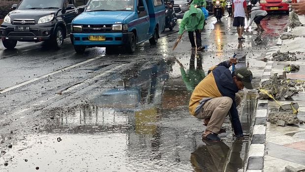 Puing bekas revitalisasi trotoar di Jalan Margonda diangkat dari saluran drainase saat terjadi genangan air, Senin (19/12/2022).
