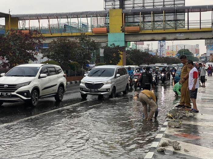 Puing bekas revitalisasi trotoar di Jalan Margonda diangkat dari saluran drainase saat terjadi genangan air, Senin (19/12/2022).
